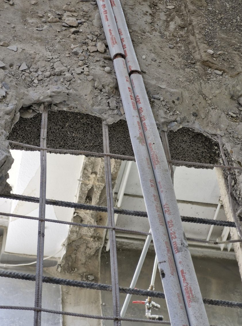 Ausgestemmter Beton mit Bewehrung und Leitungen